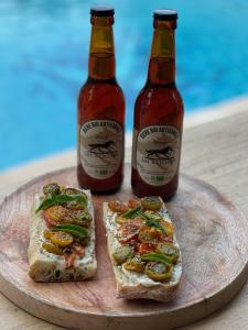 two bottles of beer sitting on a wooden plate with sandwiches at Les jardins de Manotte in La Motte