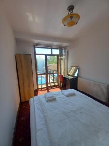 Un dormitorio con una gran cama blanca y una ventana en Хотел Макензен, en Melnik