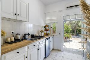 a kitchen with white cabinets and a sink at Ourania Studios & Apartments in Skopelos Town
