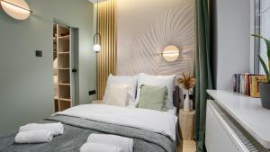 sypialnia z łóżkiem z białymi i zielonymi poduszkami w obiekcie Apartamenty Sun & Snow Sosnowy Zakątek w mieście Mrzeżyno