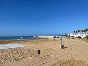 uma praia arenosa com palmeiras e o oceano em AcquaChiara em Marina di Ragusa