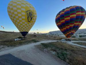 três balões de ar quente a voar sobre uma estrada de terra batida em Perla Cappadocia em Goreme