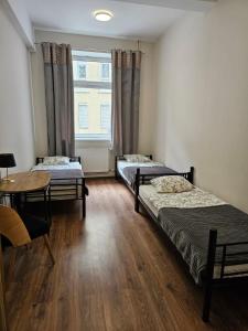 a room with three beds and a table and a window at Hostel KASZUBSKA in Wrocław