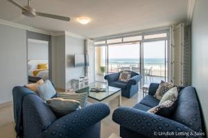 a living room with blue furniture and a view of the ocean at COZUMEL 213 in Umdloti