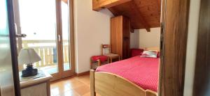ein Schlafzimmer mit einem Bett mit einer roten Bettdecke und einem Fenster in der Unterkunft Mansarda a Carciato, trilocale in montagna in Dimaro