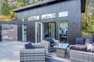 una casa nera con terrazza arredata con sedie e tavoli di Newly built Luxurious Guest house ad Åkersberga