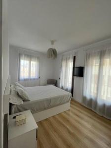 a white bedroom with a bed and two windows at Apartamento Las Vistas in Teruel