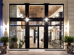 New Hotel Le Quai - Vieux Port في مارسيليا: واجهة متجر مع أبواب زجاجية كبيرة مع نباتات في الأمام