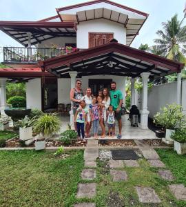 a family standing in front of a house at Fourcoock Villa in Kosgoda