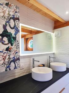 La salle de bains est pourvue de 2 lavabos et de papier peint à fleurs. dans l'établissement Cabanes du Domaine des Fées, à Dole