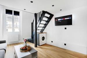 a living room with a staircase and a tv at Cosy renovated 1BDR on rue des Archives Marais Clim 5 in Paris