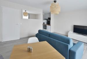 een woonkamer met een blauwe bank en een tafel bij La Villa des Arts in Évry-les-Châteaux