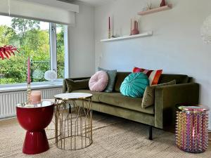 uma sala de estar com um sofá verde e duas mesas em Gezellig en luxe chalet met zicht op het water em Erm