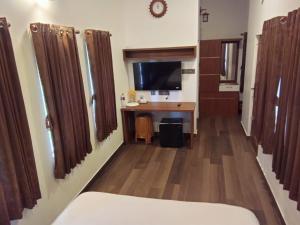 a hotel room with a desk and a television at Thekkekara Tourist Home Vagamon in Vagamon