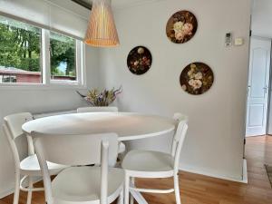 een witte eetkamer met een witte tafel en stoelen bij Gezellig en luxe chalet met zicht op het water in Erm