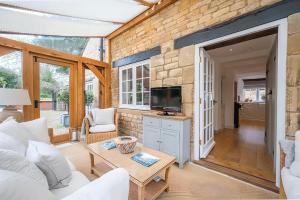 a living room with a white couch and a tv at High House in Chipping Campden