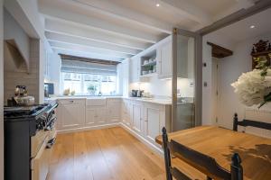 a kitchen with white cabinets and a wooden table at High House in Chipping Campden