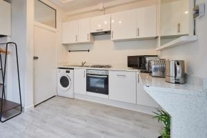a kitchen with white cabinets and a washer and dryer at Host & Stay - Cosy Twickenham Rugby Gem in Twickenham