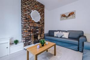 a living room with a blue couch and a brick fireplace at Beautiful Townhouse Near City Free Parking Onsite in Wallasey