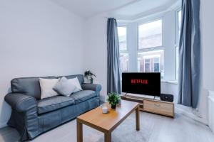 uma sala de estar com um sofá azul e uma televisão em Charming Urban Oasis -Free Parking, Close to City em Wallasey