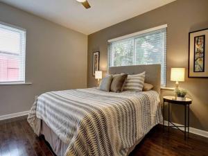 a bedroom with a bed with a blanket and two windows at Bright 2BR near downtown in Cincinnati