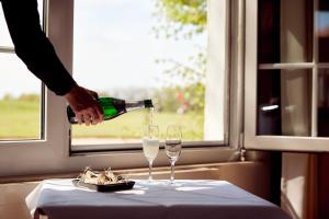 a person pouring wine into two glasses on a table at Van der Valk Golfhotel Serrahn - Adult Only in Serrahn