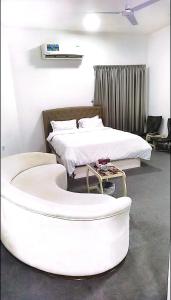 شقة السلمة أم القيوين في أم القيوين: غرفة نوم مع سرير وحوض استحمام أبيض كبير