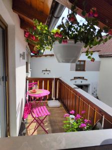 uma varanda com uma mesa rosa, cadeiras e flores em Ferienwohnung Lay em Hirschaid