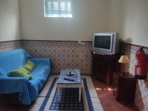 a living room with a blue couch and a tv at Casas da Estrela in Gouveia
