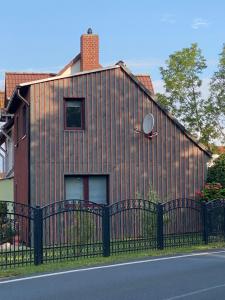 uma casa com uma cerca preta ao lado de uma rua em Küstenkind - 3 Schlafzimmer - 5 Personen em Lobbe