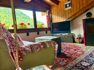 a living room with a tv and a couch and a chair at Mansarda luminosa in La Thuile