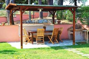 a wooden gazebo with a wooden table and chairs at Casa Papacqua in Castellina Marittima