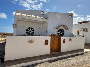 uma casa branca com um portão de madeira em frente em Villa Zembretta em El Haouaria