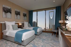 a hotel room with two beds and a large window at Cantonal Hotel by Warwick in Riyadh