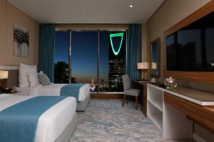 a hotel room with two beds and a large window at Cantonal Hotel by Warwick in Riyadh