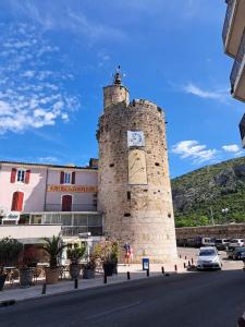 un edificio con una torre dell'orologio sul lato di una strada di Conteneur face aux vignes a Massillargues-Attuech