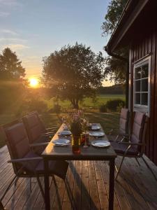- une table en bois avec des chaises sur une terrasse au coucher du soleil dans l'établissement Fjällbacka Villa, à Fjällbacka