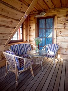 una terrazza in legno con tavolo in vetro e 2 sedie di Toomalõuka Tourist Farm a Toomalõuka