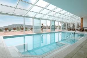 a woman walking by a swimming pool in a building at Pierre & Vacances Premium Residence & Spa Houlgate in Houlgate