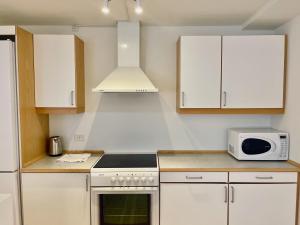 een keuken met witte kasten, een fornuis en een magnetron bij Large 5 Bedroom Flat in Lovely Urban Area in CPH Ø in Kopenhagen