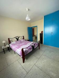a bedroom with a bed with a purple comforter and blue cabinets at Superbe maison à M'diq in M'diq