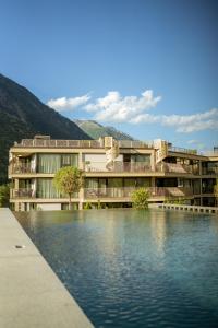 a building with a lake in front of it at Boutique Hotel AMARIL in Castelbello-ciardes