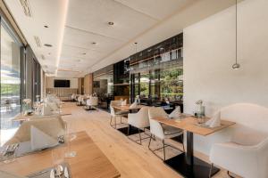 ein Restaurant mit Holztischen und weißen Stühlen in der Unterkunft Boutique Hotel AMARIL in Kastelbell