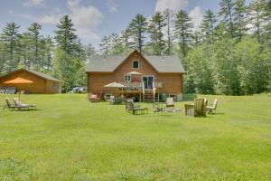 a log cabin with chairs and tables in a yard at Spacious Cabin with Private Dock on Thompson Lake in Oxford