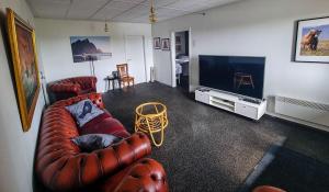 uma sala de estar com um sofá de couro e uma televisão de ecrã plano em Vikingcafe em Höfn
