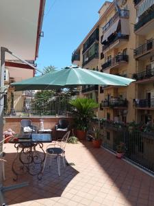 eine Terrasse mit einem Tisch und einem grünen Sonnenschirm in der Unterkunft La Terrazza di Monica & Teresa in Portici
