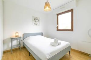 ein weißes Schlafzimmer mit einem Bett und einem Fenster in der Unterkunft Le Daubenton in Dijon