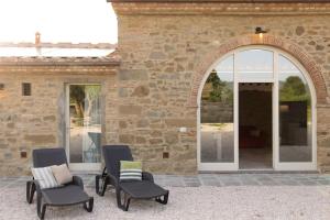 un patio avec deux chaises en face d'un bâtiment dans l'établissement Villetta Montalla, à Cortone