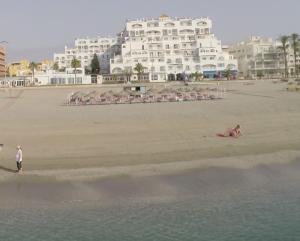 uma pessoa na praia com um hotel ao fundo em Bahía Serena em Roquetas de Mar