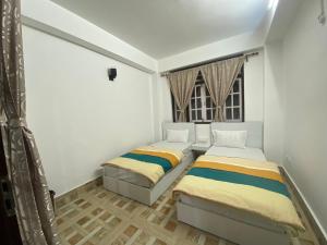 2 camas en una habitación con ventana en Zongkha Homestay en Gangtok